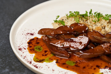 Baked lamb tongues with spicy bulgur porridge in a white plate