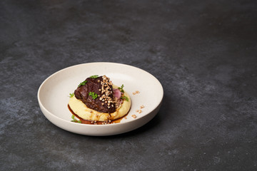 Stewed veal cheeks with mashed potatoes on a white plate, close-up.
