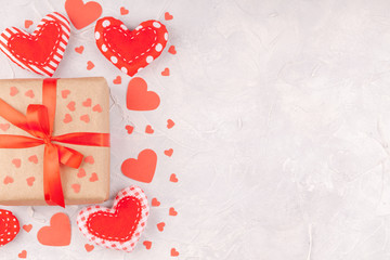 Valentine's Background with Gift Box with Red Ribbon Bow and Confetti Paper and Handmade Textile Hearts on Concrete Background. Love, Romance, Happy Valentines Day Concept. Top View, Copy Space