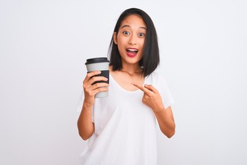 Fototapeta premium Young chinese woman drinking take away glass of coffee over isolated white background very happy pointing with hand and finger