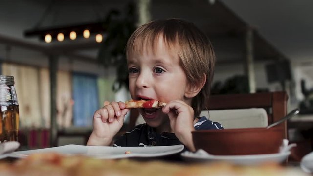 Close up of little cute boy eating pizza. Neutral colors for collor correction.