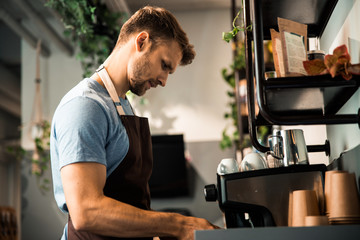 Young man standing near professional coffee machine