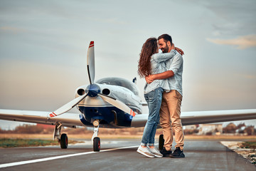 Stylish couple standing near a plane at the airport.