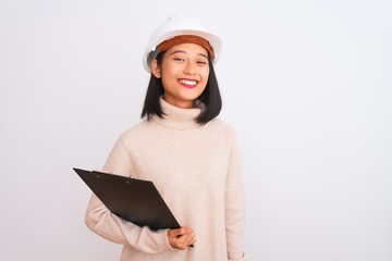 Chinese architect woman wearing helmet holding clipboard over isolated white background with a happy face standing and smiling with a confident smile showing teeth