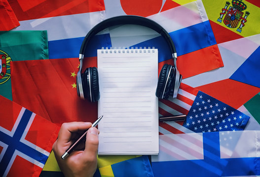 Learning foreign languages. Audio language courses. Background from countries flags and headphones on the table.