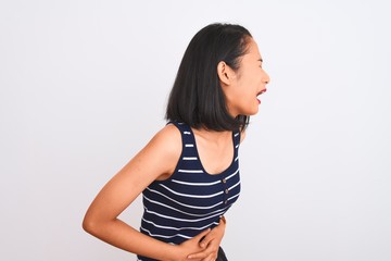 Obraz premium Young chinese woman wearing striped t-shirt standing over isolated white background with hand on stomach because indigestion, painful illness feeling unwell. Ache concept.