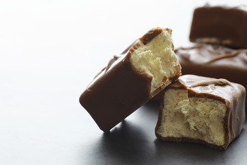 Chocolate bars on a black background in backlight. Chocolate with filling. Sweet sweets for snack and tea.