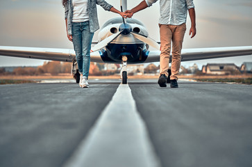 Trendy young couple walking from private plane