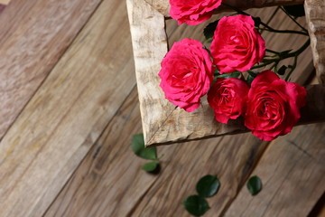 festive background with roses in a frame on a wooden table