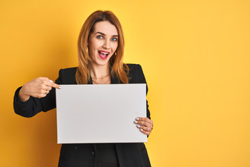 Fototapeta na wymiar Redhead business caucasian woman holding banner over yellow isolated background very happy pointing with hand and finger