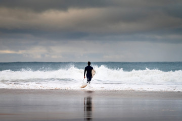Fototapeta na wymiar A surfer entering the sea at the Carcavelos Beach in Oeiras, Portugal