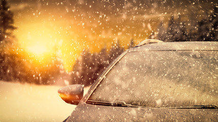 Winter car cover of frost and cold december sunse tt ime with snow flakes. 