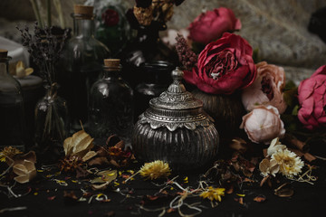 vintage jars, bottles, containers, flowers in smoke and dry leaves on a wooden table with warm light