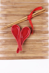 Valentine's day, mother's day, woman's day concept. Set of sushi on mat of chopsticks. Red suchi dishes and chopsticks tied red tape on wooden background. Top view with place for text.
