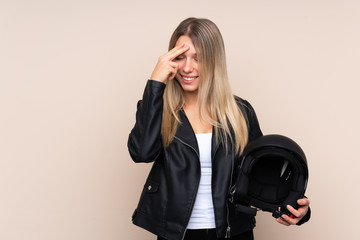 Young blonde woman with a motorcycle helmet over isolated background laughing