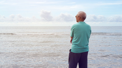 Elder senior Asian man sitting alone at ocean coastline