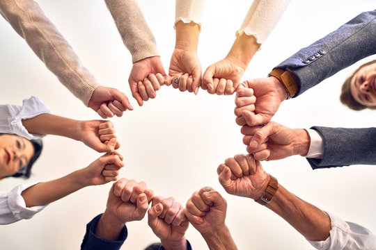 Group of business workers standing bumping fists at the office