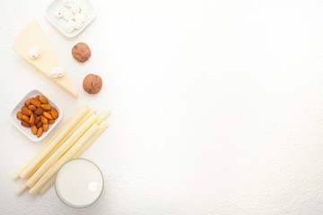 Cheeses, almonds, and milk are placed on a white background, top view, and there is space for text. The concept of products containing calcium.
