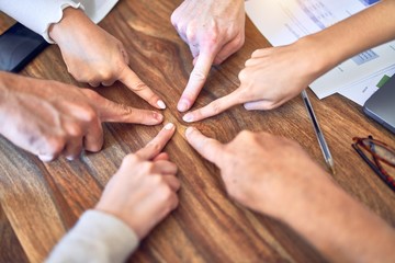 Group of business workers standing with hands together. Doing symbol with fingers at the office