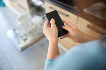 Housewife with cellphone in kitchen stock photo