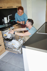 Happy couple near dishwasher in kitchen stock photo