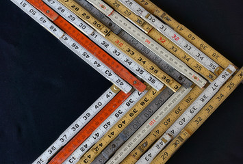 Folding rulers in metric and inches on black background form a chevron chart or graph representing...