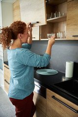Smiling woman at cupboard in kitchen stock photo