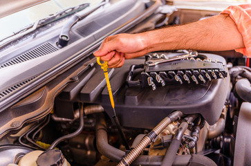 Male mechanic checking car engine oil level and change