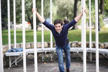 A young man walks in the park at lunch time. A man is on a walk in the city. A student in the park.