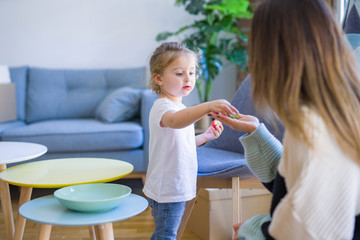 Lovely toddler child girl with her young beautiful mum eating strawberry