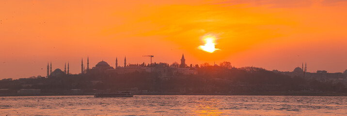 Istanbul Bosporus and city ferries with the silhouette of Hagia Sophia during sunset golden hour