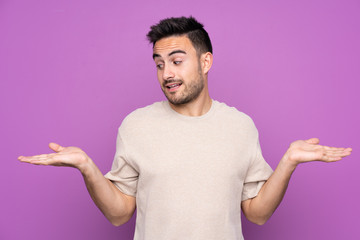 Young handsome man over isolated purple background holding copyspace with two hands