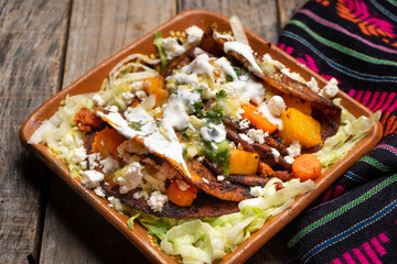 Mexican red enchiladas with potato and pork chorizo also called Potosinas on wooden background