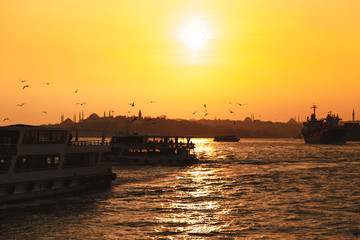 Istanbul Bosporus and city ferries with the silhouette of Hagia Sophia during sunset golden hour