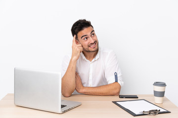 Fototapeta premium Young business man with a mobile phone in a workplace having doubts and with confuse face expression