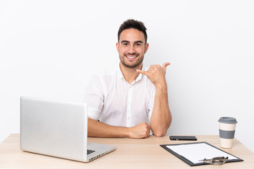 Young business man with a mobile phone in a workplace making phone gesture