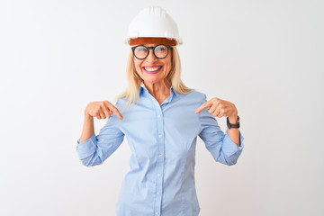 Middle age architect woman wearing glasses and helmet over isolated white background looking confident with smile on face, pointing oneself with fingers proud and happy.