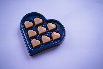 Chocolate bonbons with heart shape on purple background. Saint Valentine's concept.