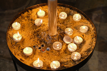 Large sand dish use to display tea lights lit by members of the public. Located in a well-known cathedral.