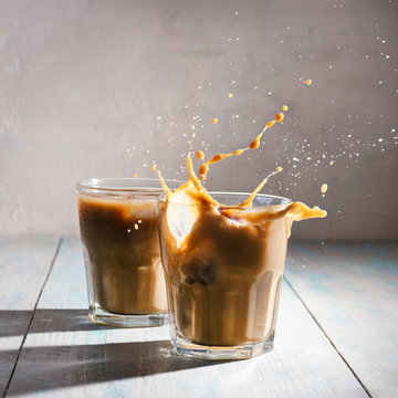 Splash in iced coffee on wooden background