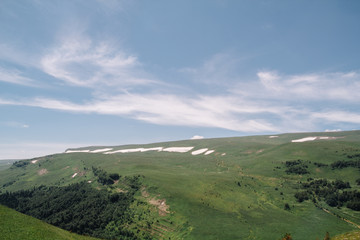 Fototapeta premium Summer view of the plateau lago naki with snow. Beautiful clouds and mountain in a blue haze.
