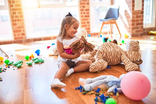 Young beautiful blonde girl kid enjoying play school with toys at kindergarten, smiling happy playing with stuffed animal at home at home