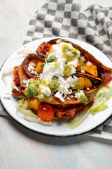 Mexican red enchiladas with potato and pork chorizo also called Potosinas on wooden background