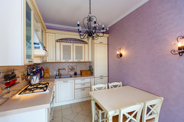 Luxury rich modern beige kitchen in Provence style, pink wall, forged black chandelier