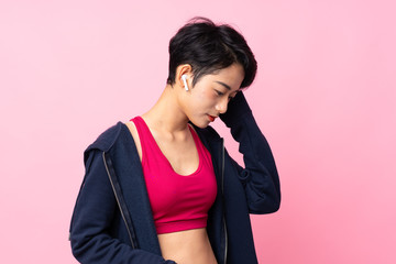 Young sport Asian woman over isolated pink background listening music