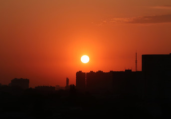 Bright orange sunset and big sun over the city on a hot sultry summer evening