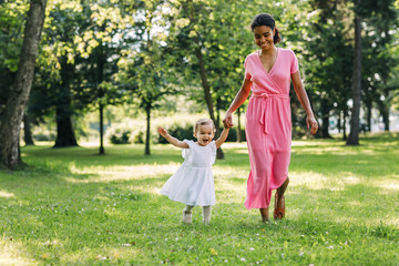 Fototapeta premium Young mother and her happy daughter run in the park 