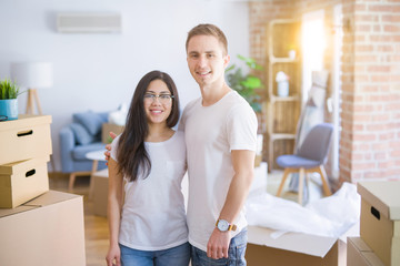 Young beautiful couple standing at new home around cardboard boxes