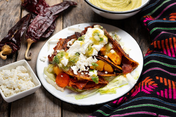 Mexican red enchiladas with potato and pork chorizo also called Potosinas on wooden background