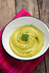 Mexican creamy green sauce with jalapeno pepper on wooden backgrond